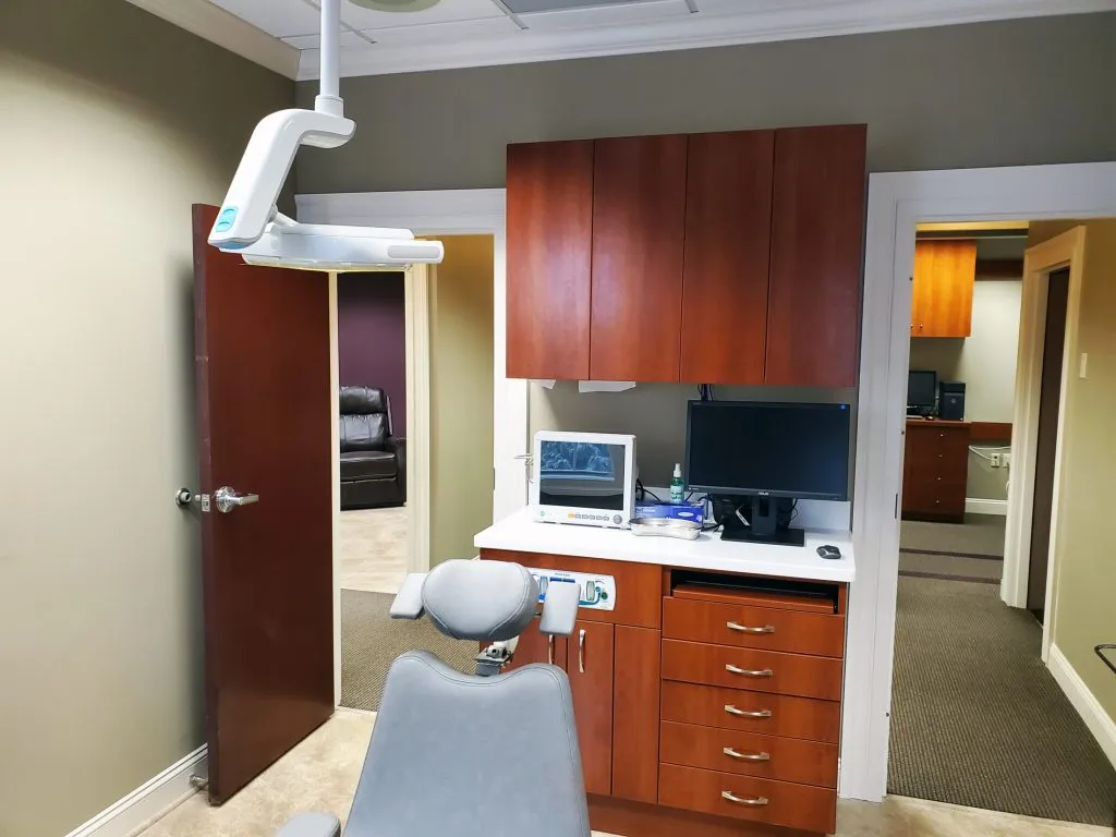 Dental chair and computer in patient room at {PRACTICE_NAME}