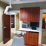 Dental chair and computer in patient room at {PRACTICE_NAME}