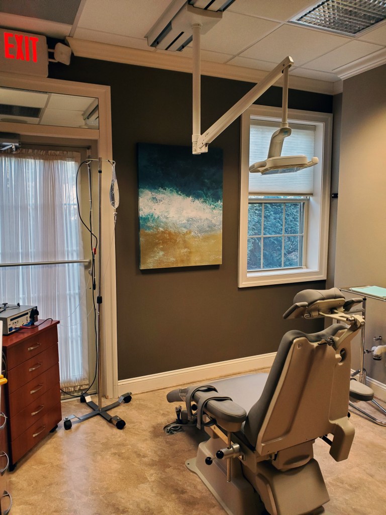 Dental chair, overhead light, and IV in patient room at {PRACTICE_NAME}